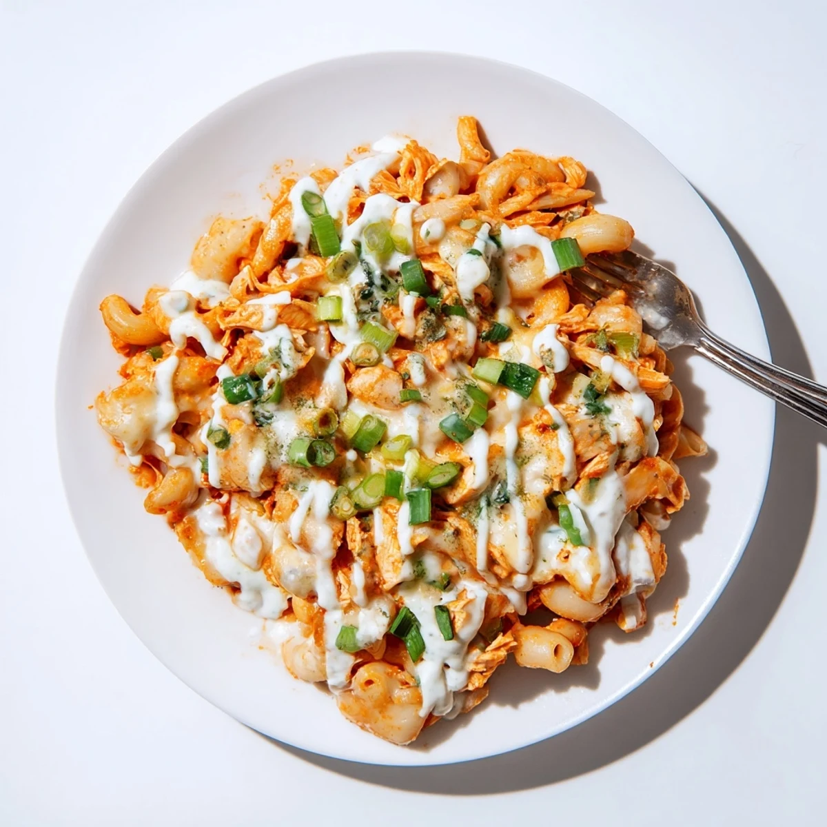 Creamy Buffalo Chicken Pasta topped with ranch drizzle and melted cheese goodness.  