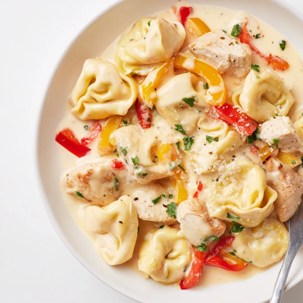 Zesty Cajun Garlic Parmesan Chicken Tortellini served with fresh parsley and extra cheese.  