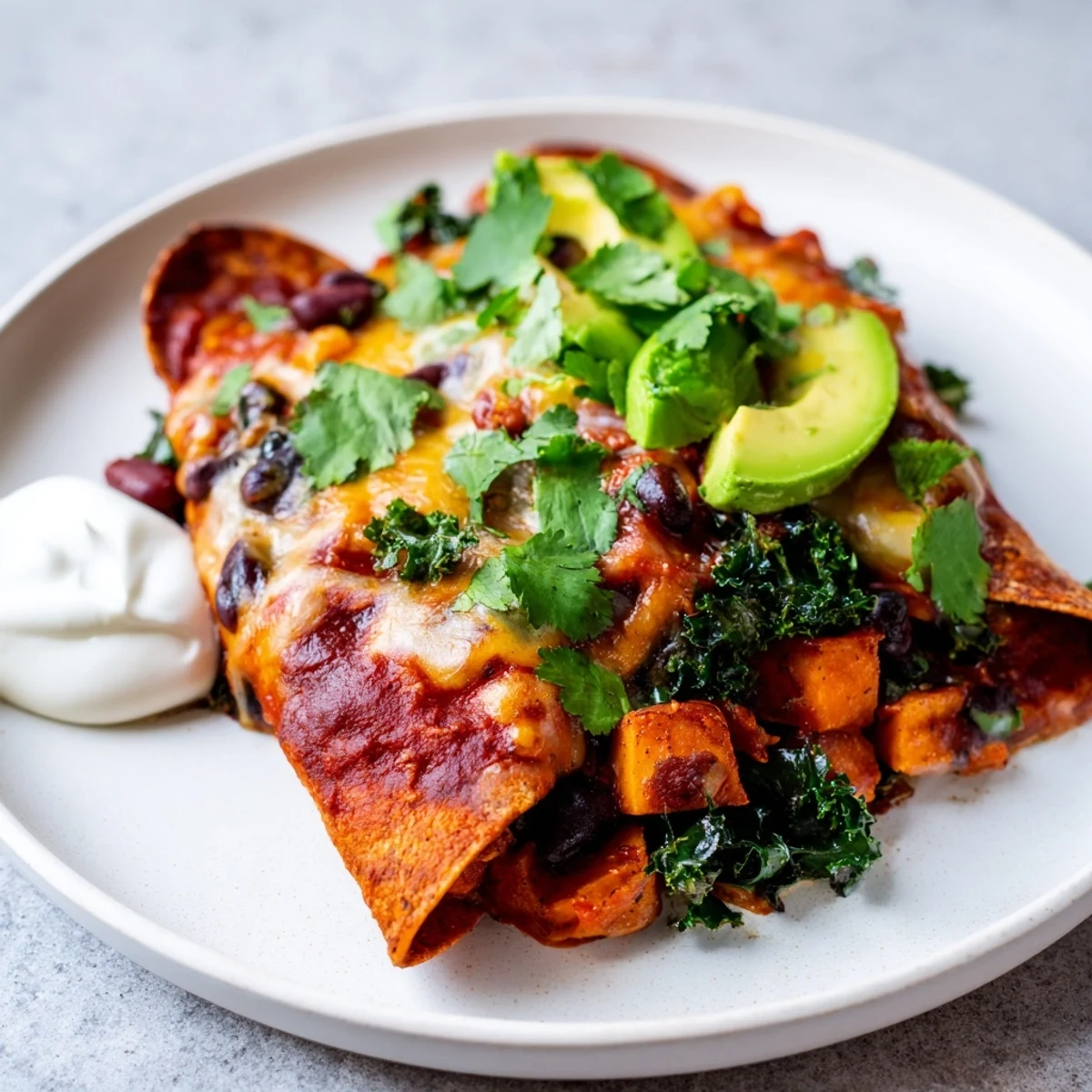Golden-brown One-Pan Sweet Potato, Black Bean & Kale Enchiladas, baked with melted cheese and fresh herbs.