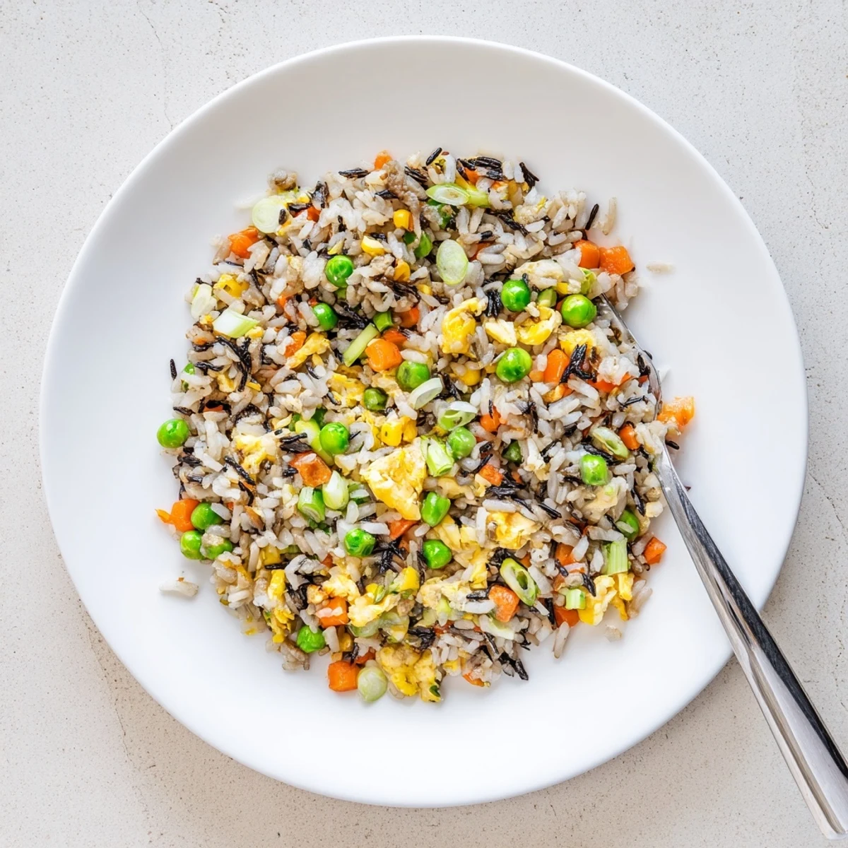 Black garlic fried rice is tossed with scallions and sesame oil, steaming fragrantly in a skillet beside a small bowl of toppings.