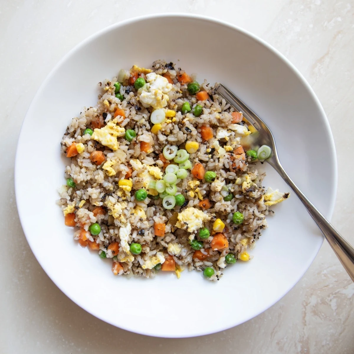 Hot jasmine rice sizzles with black garlic, peas, and carrots in a wok, creating a savory fried rice dish ready for serving.