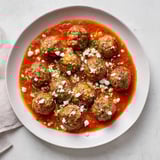 A close-up of steaming Instant Pot Greek Meatballs, showcasing the juicy texture and feta sauce.