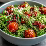 Overhead view of the Arugula Pesto Bowl, showcasing golden roasted peppers and fresh arugula tossed in green pesto.