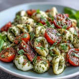 Caprese Pasta Salad: vibrant tomatoes, mozzarella pearls, and pesto create a refreshing summer dish.