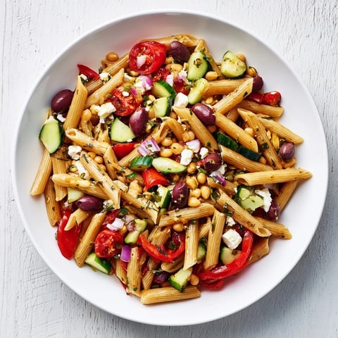 Mediterranean pasta salad with chickpeas, bursting with fresh veggies and tangy feta, ready to serve.
