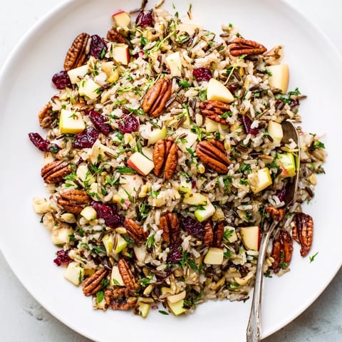 Wild Rice Harvest Salad in a rustic bowl, showcasing glossy cranberries and golden toasted pecans on nutty grains.