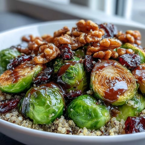 Golden roasted Brussels sprouts with caramelized edges and red onion slices piled high over fluffy quinoa in a nourishing bowl.