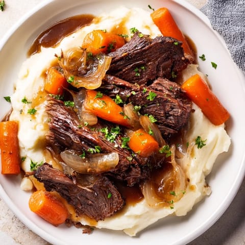 A close-up of a warmly colored Slow Cooker Pot Roast with visible hearty vegetables and potatoes.