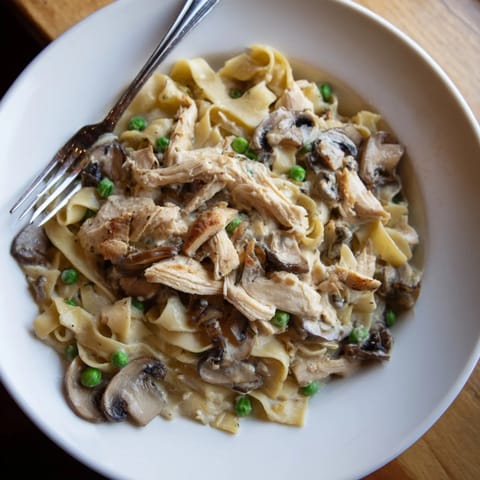 Creamy chicken Alfredo slow-cooker meal, perfectly plated with fettuccine pasta, ready to eat alongside a salad.