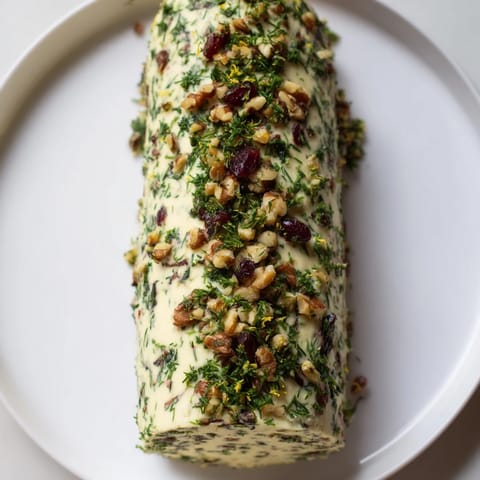 A close-up of a Winter Snowdrift Goat Cheese Log, ready to be served with crackers and honey.