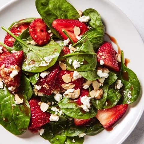 A beautiful bowl of Strawberry Spinach Salad, with bright red strawberries and a creamy dressing.