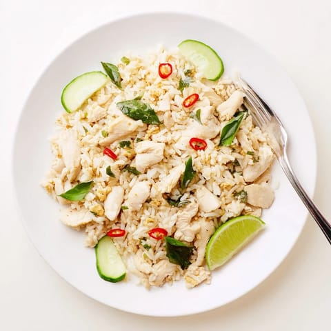 Spicy Thai Basil Chicken Fried Rice wok-fried with chicken, chilies, and jasmine rice, garnished with lime and fresh cucumber.  