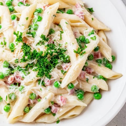 Spring Pea & Ham Pasta served hot, garnished with fresh parsley, bright peas, and diced ham in a skillet.  