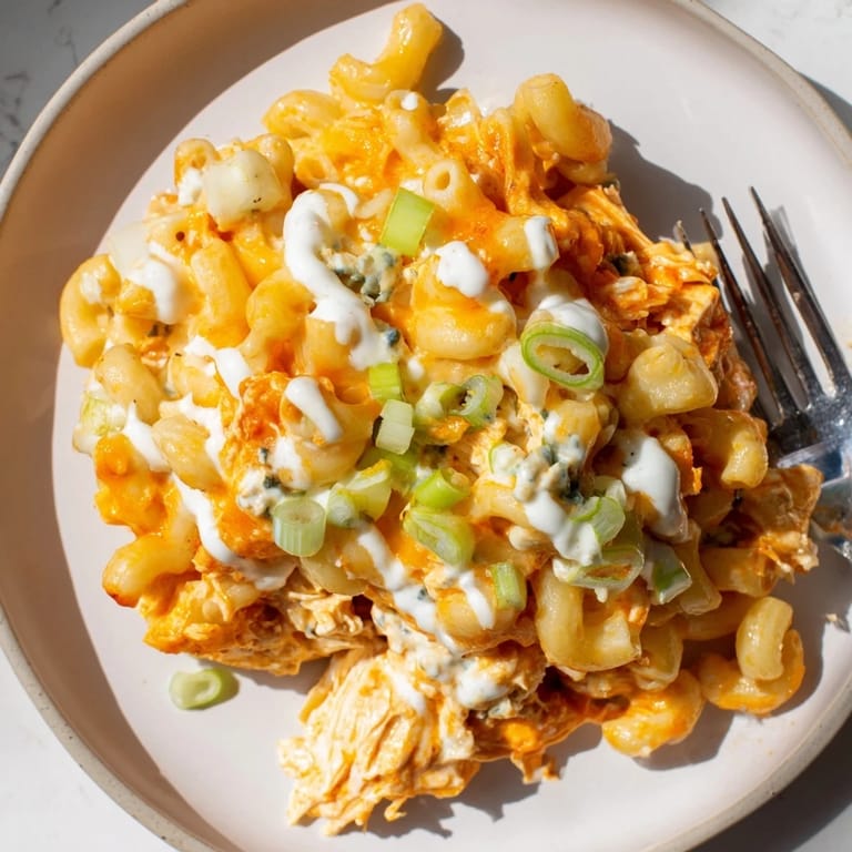 Spicy Buffalo Chicken Pasta dish, drizzled with ranch and garnished with green onions.