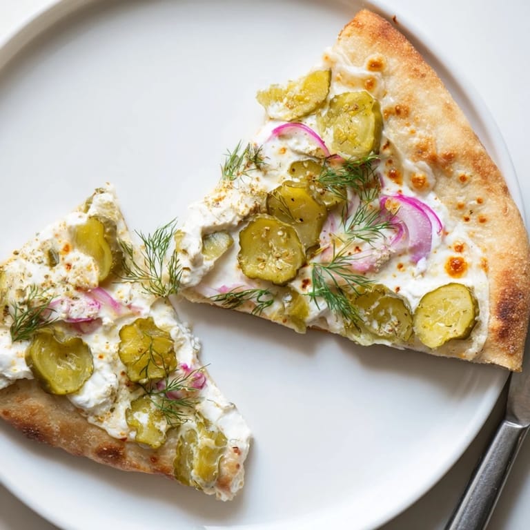 Deliciously unique Pickle Pizza garnished with fresh dill and zesty red onion slices.