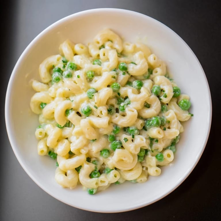 A steaming skillet of creamy Macaroni & Peas, bubbling with flavorful sauce and green peas.