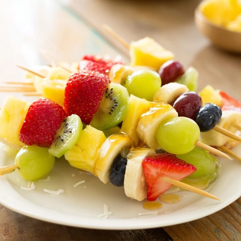 Quick and easy Easy Festive Fruit Kabobs, ready to enjoy with a drizzle of honey and coconut flakes.