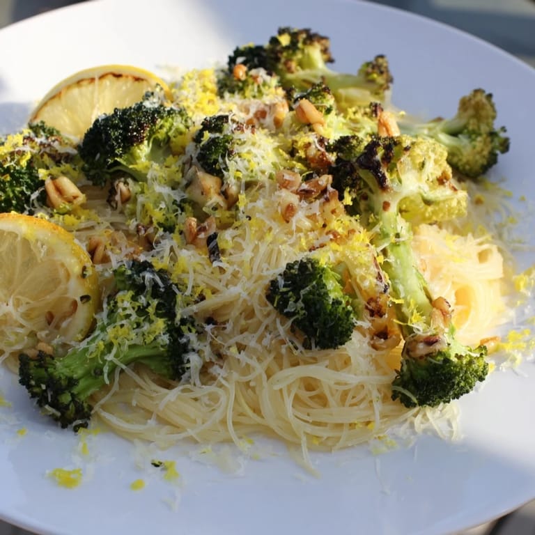 A close-up of Roasted Garlic Lemon Broccoli Angel Hair Pasta, steaming and ready to eat with Parmesan.
