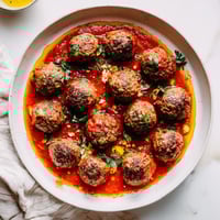 Instant Pot Greek Meatballs smothered in vibrant tomato sauce with a creamy lemon-feta topping.