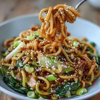 Asian Ginger Scallion Noodles with Sautéed Greens in a savory ginger-scallion sauce, topped with vibrant bok choy and snap peas.